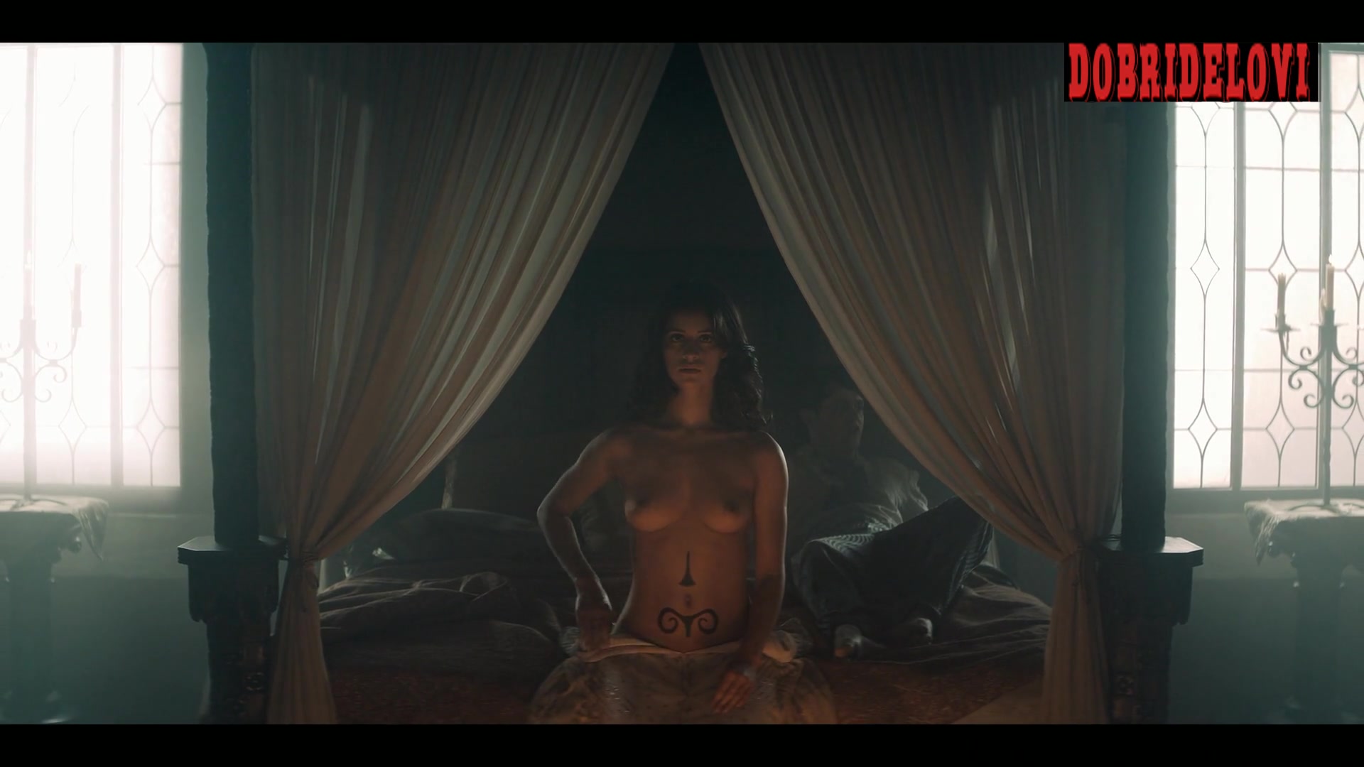 Anya Chalotra sits topless in bed doing some magic